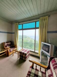 a living room with a couch and a large window at Bird's Nest in Bhurban