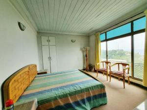 a bedroom with a bed and a large window at Bird's Nest in Bhurban