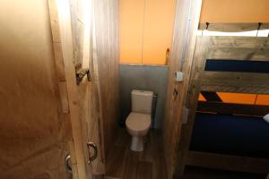 een kleine badkamer met een toilet en een deur bij De Zuidvliet Glamping Deluxe 1 in Wolphaartsdijk
