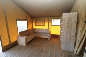 een kamer met een bank en een gele muur bij De Zuidvliet Glamping Deluxe 1 in Wolphaartsdijk