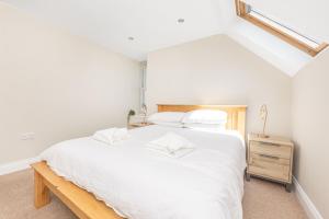 um quarto com uma cama branca e uma cómoda em madeira em Bay View Apartments em Port Erin
