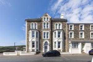 a large brick building with a car parked in front of it at Bay View Apartments in Port Erin