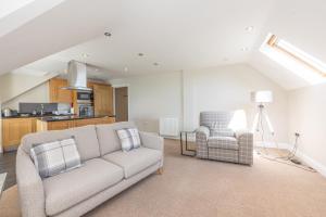 a living room with a couch and two chairs at Bay View Apartments in Port Erin