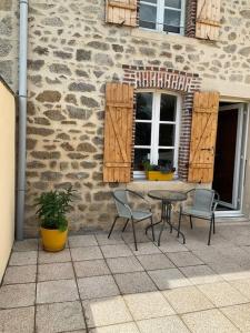 eine Terrasse mit einem Tisch und Stühlen vor einem Gebäude in der Unterkunft La Petite Maison in Saint-Dizier-Leyrenne