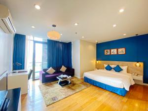 ハノイにあるMy Way Hotel & Residence Ha Noiの青い壁のベッドルーム1室、ベッド1台、ソファが備わります。