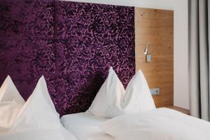 a bed with white pillows and a purple wall at Alpina Wagrain in Wagrain