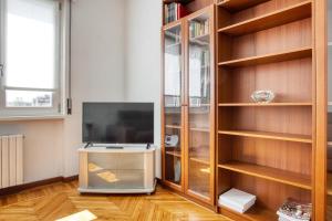 ein Wohnzimmer mit einem TV und Holzregalen in der Unterkunft JOIVY Cosy apt in the Giambellino area in Mailand