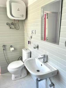 Un baño con un inodoro blanco y un lavabo. en Satobari Greens Homestay, en McLeod Ganj