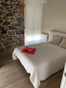 sypialnia z białym łóżkiem z czerwonym ręcznikiem w obiekcie Precioso Piso muy cerca de la playa de salinas, Eysines 34 1izq w mieście Piedras Blancas
