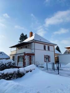 uma casa coberta de neve em frente a uma cerca em Haus-Holidayde Bad Sachsa Harz em Bad Sachsa