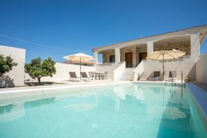 a swimming pool with chairs and umbrellas in front of a house at Anastasia Luxury House in Afantou