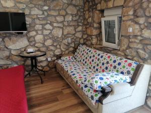 a couch in a room with a stone wall at Apartmani Perosevic in Danilovgrad