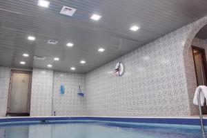 una piscina en una habitación con una pared de azulejos en البستان للأجنحة الفندقية, en Al Hofuf