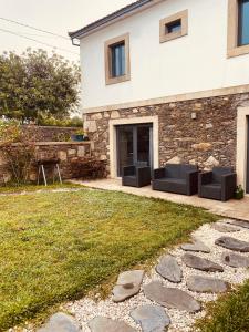 una casa de piedra con dos sofás negros en un patio en Serra de Arga Mountain House, en Montaria