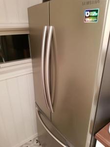 a stainless steel refrigerator in a kitchen with white cabinets at Charming beach house in Moss