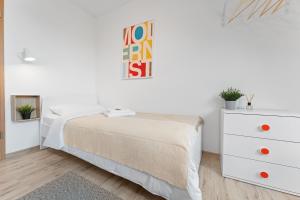 a white bedroom with a bed and a dresser at Helle moderne Wohnung, ,nahe Uni, zentral in Cottbus