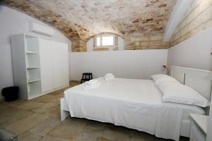 een slaapkamer met een wit bed en een bakstenen muur bij Stairway to heaven in Bari