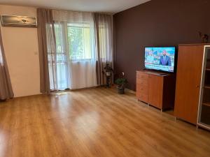 ein Wohnzimmer mit einem TV und Holzböden in der Unterkunft АПАРТАМЕНТ МАЯ in Kasanlak