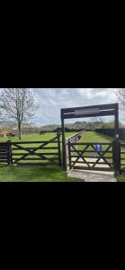 a wooden fence with a gate in a field at Tarka Holiday Park in Ashford