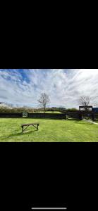 a park with two benches in a grassy field at Tarka Holiday Park in Ashford