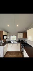 a kitchen with white cabinets and a stove top oven at Tarka Holiday Park in Ashford