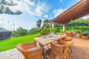 Un patio al aire libre con una mesa y sillas de madera. en Villa Es Pinaro - Beach Front, en Son Servera