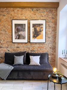 a brick wall with three pictures above a couch at Apartament Gwarek in Wałbrzych