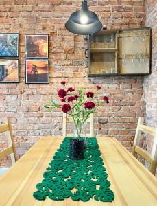 una mesa con un jarrón con flores rojas. en Apartament Gwarek, en Wałbrzych