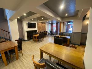 a restaurant with tables and chairs and a fireplace at Plas Coch Hotel Ltd in Bala