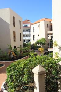 a view of a courtyard with buildings and bushes at Favoloso trilocale a Las Americas in Arona