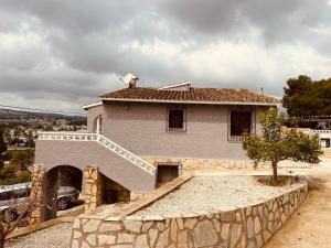 uma casa grande com uma parede de pedra em frente em La Casa Leelouka em Moraira