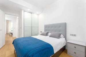 a white bedroom with a large bed with a blue blanket at House Riberas in Loyola