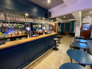 un bar con paredes y mesas azules y taburetes en Plas Coch Hotel Ltd, en Bala