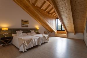 a bedroom with a large bed and a wooden ceiling at The Rock Suites & Spa in Congosto