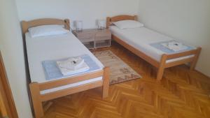 two twin beds in a room with wooden floors at Apartman Bubamara in Arilje