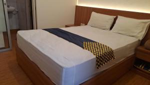 um quarto com uma cama com lençóis brancos e um cobertor azul e dourado em Bintang Khanida Syari'ah em Tjakranegara