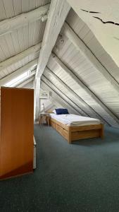 an attic room with a large bed and a cabinet at Gîtes Sous Les Loges in Lélex
