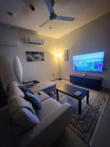 sala de estar con sofá y TV de pantalla plana en One Bedroom Al Hail DT, en Ḩayl Āl ‘Umayr