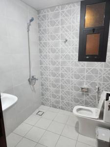 Baño blanco con aseo y lavamanos en One Bedroom Al Hail DT, en Ḩayl Āl ‘Umayr