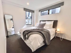 1 dormitorio blanco con 1 cama grande y espejo en Modern & Central City - By KOSH BNB en Hamilton