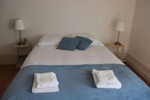 a blue and white bed with two towels on it at La Buissonnière in Arnay-le-Duc
