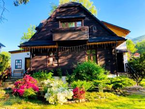 a wooden house with flowers in front of it at Odskocznia House in Szczyrk