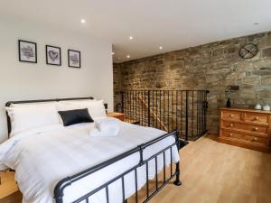 een slaapkamer met een groot bed en een stenen muur bij Hoot Cottage in Keighley