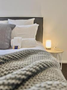 Cama con almohadas blancas y mesa con lámpara en Modern & Central City - By KOSH BNB en Hamilton