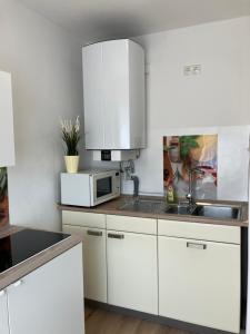 a white kitchen with a sink and a microwave at ZIMMERVERMIETUNG38 - Händel in Salzgitter