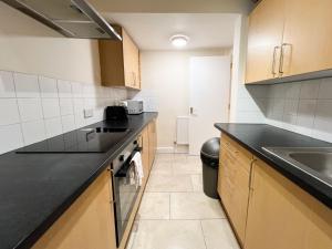 eine Küche mit schwarzen Arbeitsplatten und einem Waschbecken in der Unterkunft Convenient 2BR Basement Flat in Leith in Edinburgh