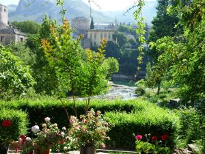a view of a garden with flowers and a river at Pansion Villa Nur in Mostar