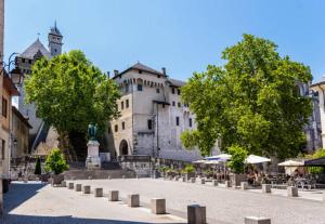 un bâtiment avec des arbres, des tables et des chaises dans une rue dans l'établissement Les Hauts du Château, à Chambéry