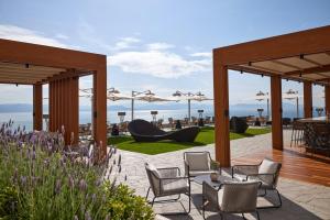 a patio with chairs and tables and a view of the ocean at Angsana Corfu Resort & Spa in Benitses