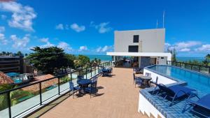 uma varanda com uma piscina e mesas e cadeiras em Apartamento com piscina no Condominio Maraca2 em Ipojuca